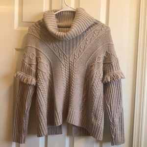 Beige knitted oversized turtleneck cropped sweater. Open V back